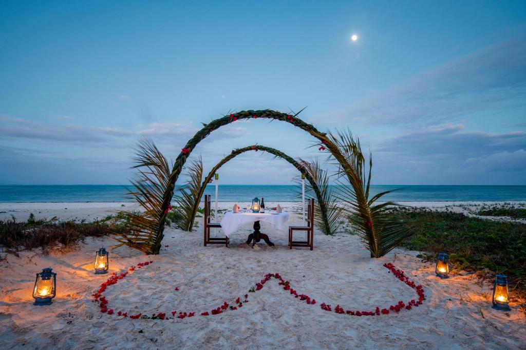 a person sitting under an arch on the beach at Hakuna Majiwe Beach Lodge in Paje