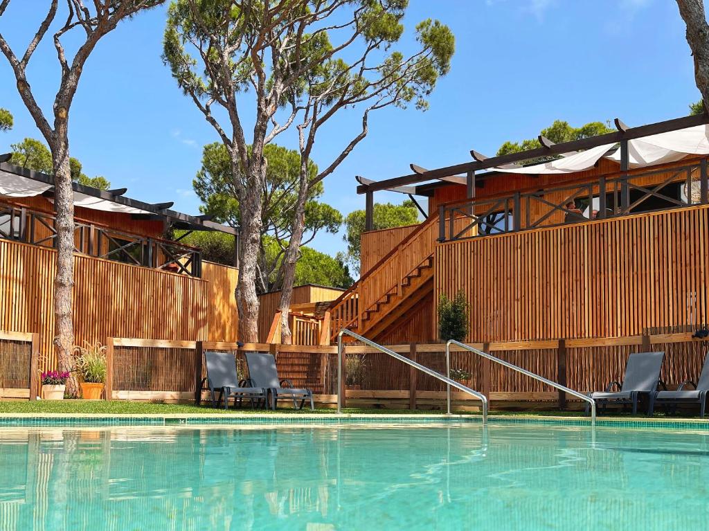 a swimming pool with chairs and a house at Nuevos Apartamentos Biopasivos Living Pura Madera in Chiclana de la Frontera