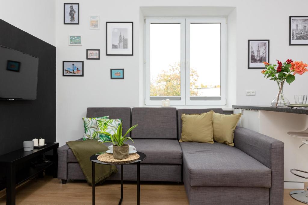 a living room with a couch and a table at Metro Młynów Warsaw Wola Apartment Długosza by Renters in Warsaw