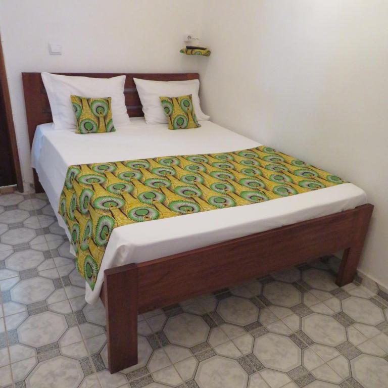 a bedroom with a large bed with a wooden frame at Micaval Residential in São Tomé