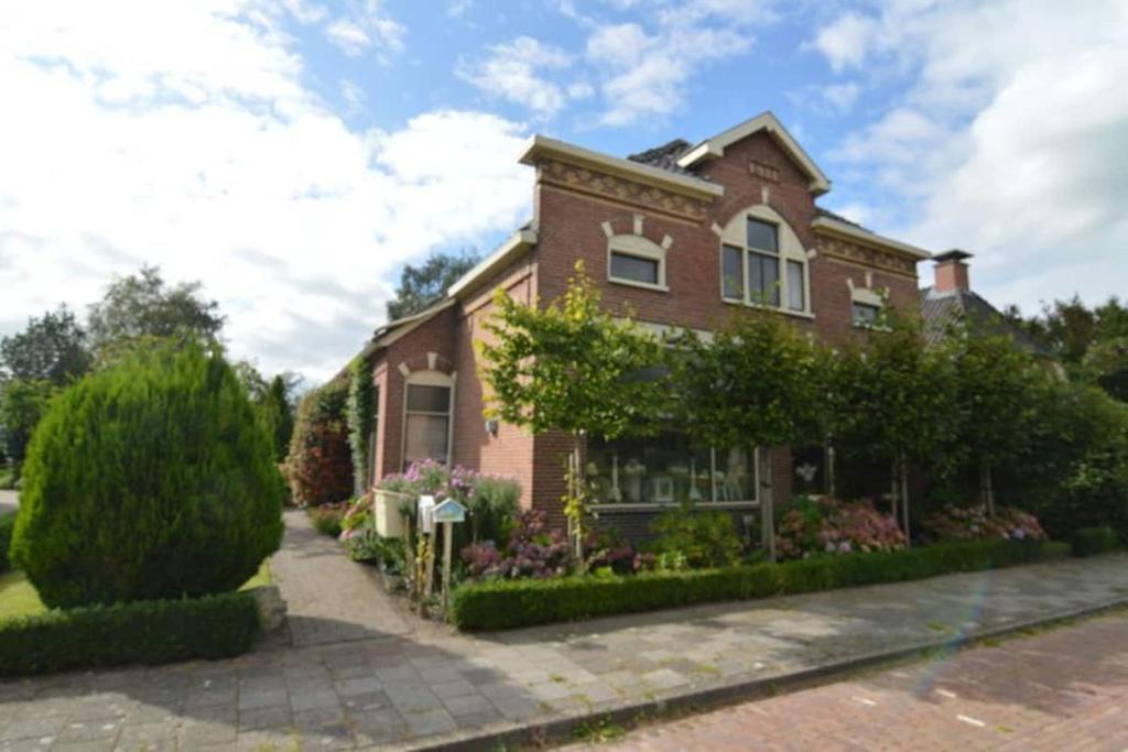 a brick house with flowers in the front yard at Ruim appartement in oude bakkerij in Gasselternijveen