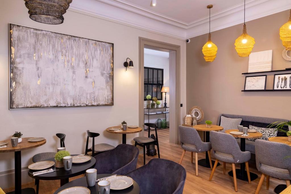 a restaurant with tables and chairs and a painting on the wall at Hôtel Le Fer à Cheval in Trouville-sur-Mer