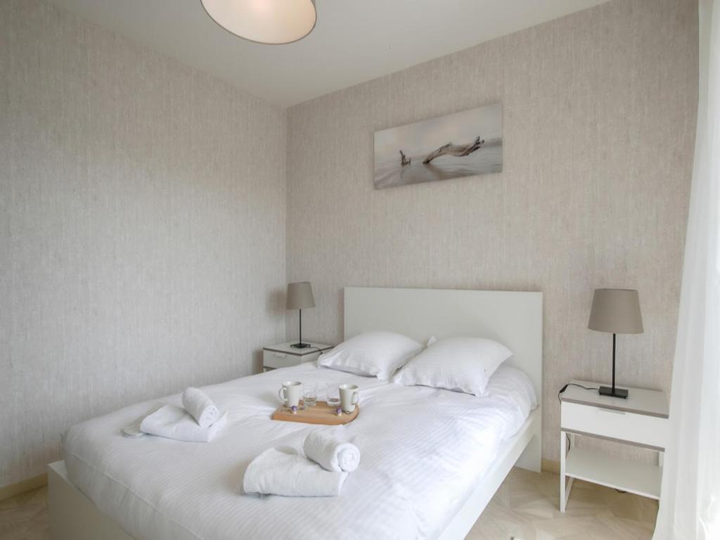 a bedroom with a white bed with towels on it at Le Gréement - Appt vue sur le port in Courseulles-sur-Mer