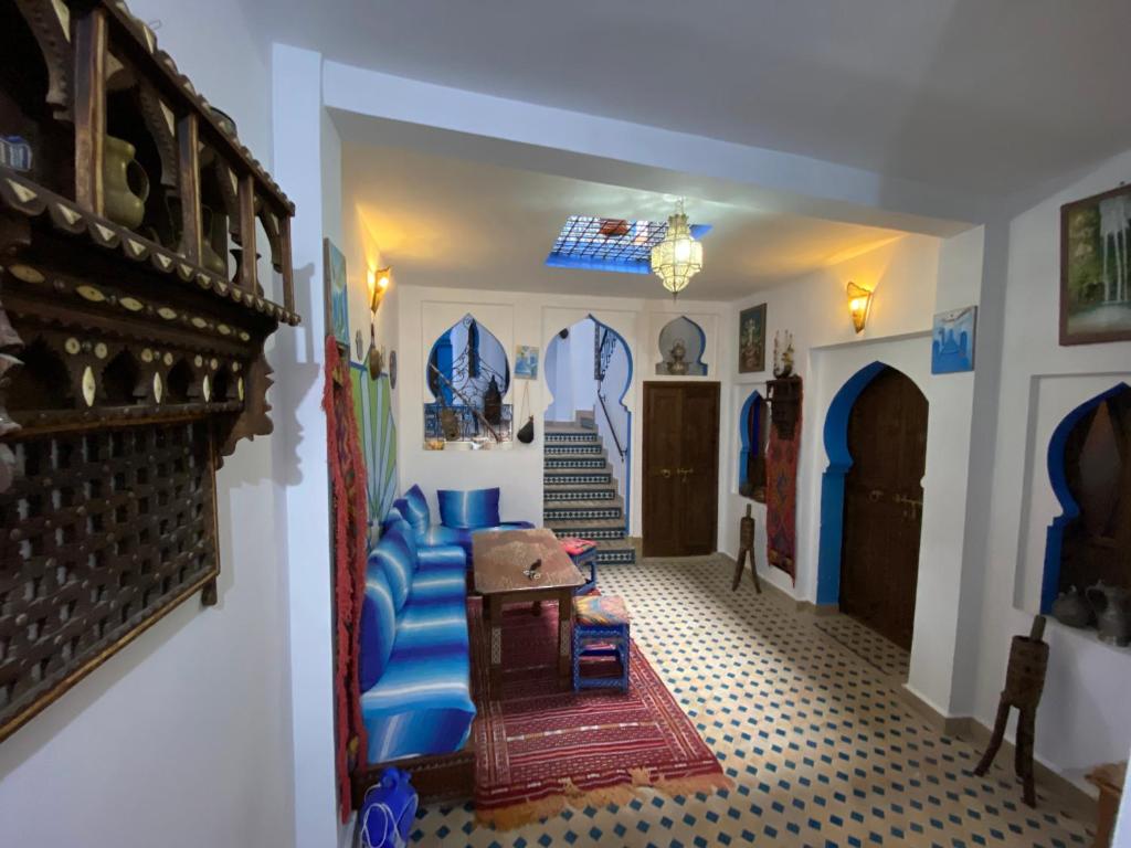 uma sala de estar com um sofá azul e uma escada em Dar Essaouyry em Chefchaouene