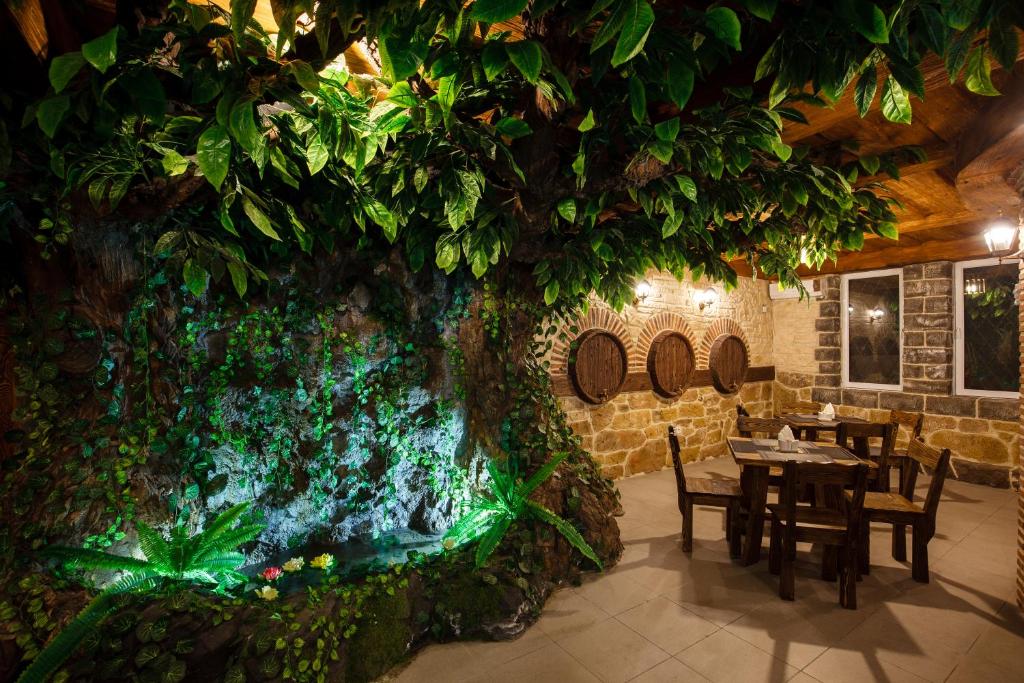 ein großer Baum in einem Restaurant mit Tischen und Stühlen in der Unterkunft Hotel Gremi Tbilisi in Tbilisi City