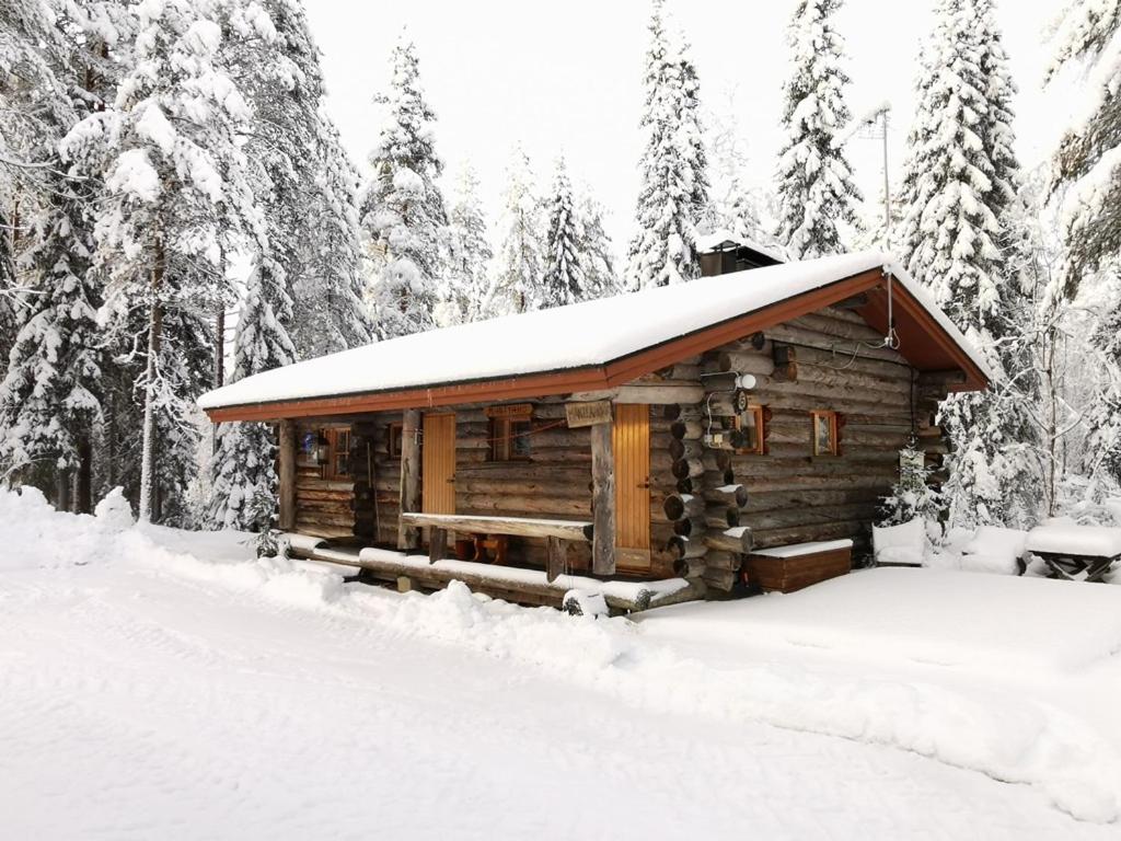 uma cabana de madeira na neve com árvores em Mäntyaho em Syöte