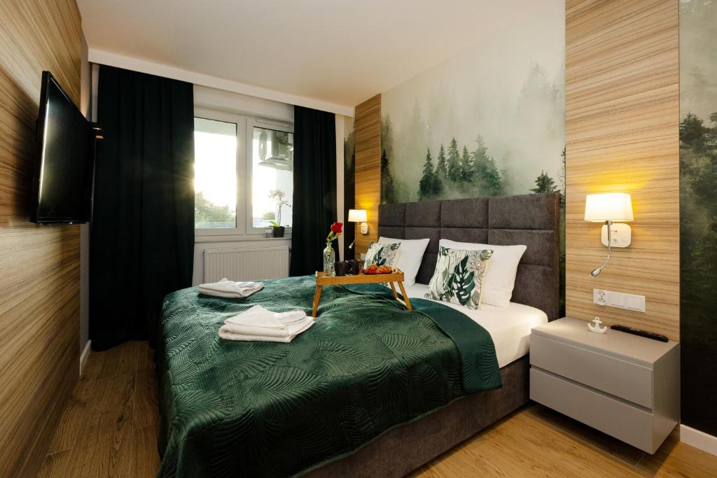 a bedroom with a bed with a green blanket at Apartamenty Perłowa Przystań by Renters in Kołobrzeg