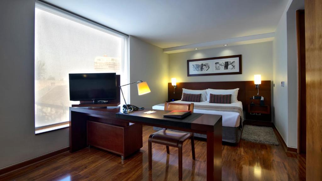 1 dormitorio con 1 cama y escritorio con TV en Select by Time, en Santiago