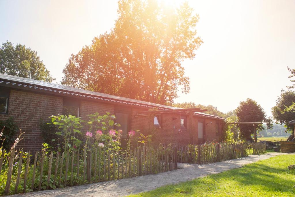 a house with a wooden fence in the yard at Huisje en B&B Green Cottage in Groesbeek