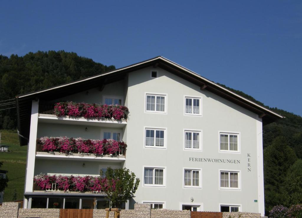 ein weißes Gebäude mit Blumen auf den Balkonen in der Unterkunft Ferienwohnungen Kern in Weyregg