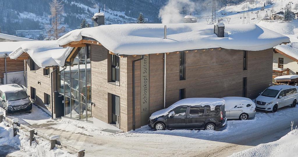 a house with cars parked outside of it in the snow at Schlosskopf Suiten in Sankt Anton am Arlberg