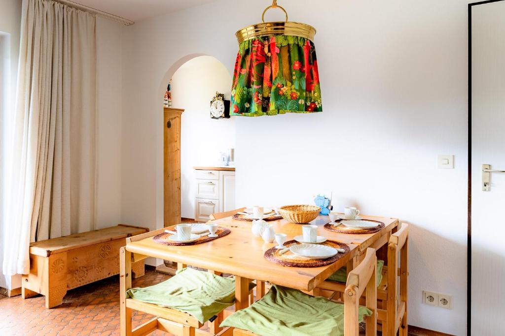 una sala da pranzo con tavolo in legno e lampadario pendente di Huflattich a Obermaiselstein