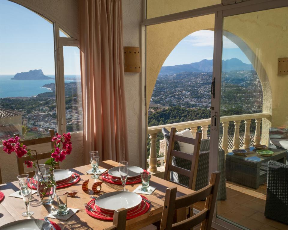 a dining room table with a view of the city at Casa Inca, Villa with heatable pool and top view atop Moraira El Portet in Cumbre del Sol