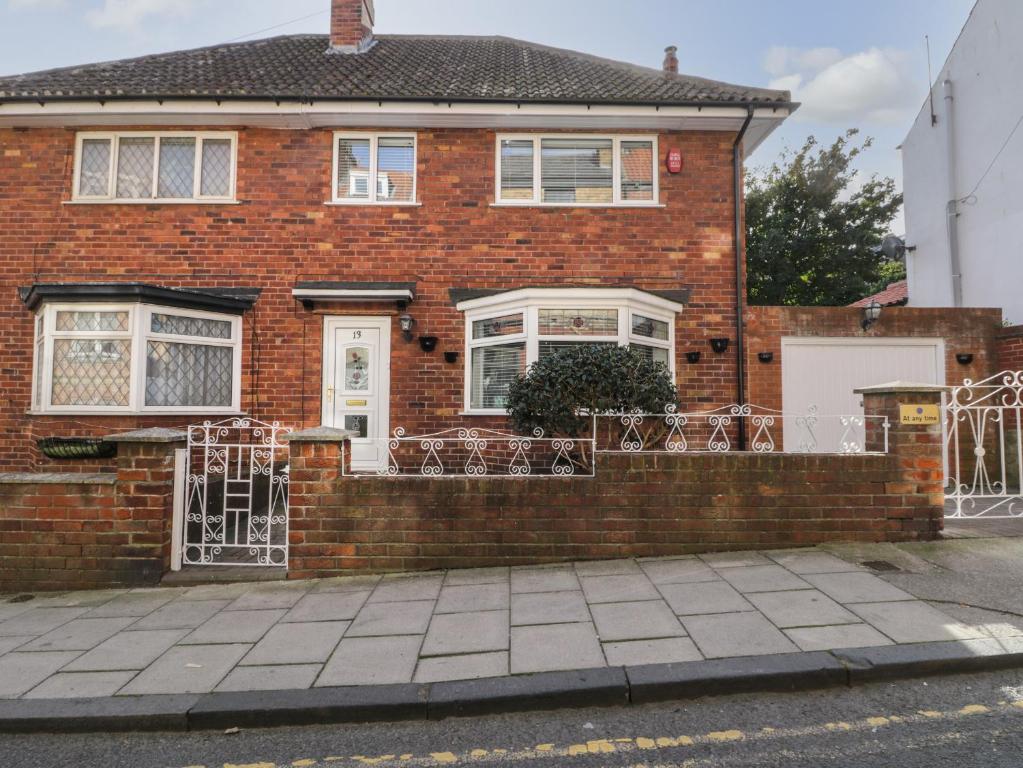a brick house with white doors and a fence at Sally's Berth in Scarborough