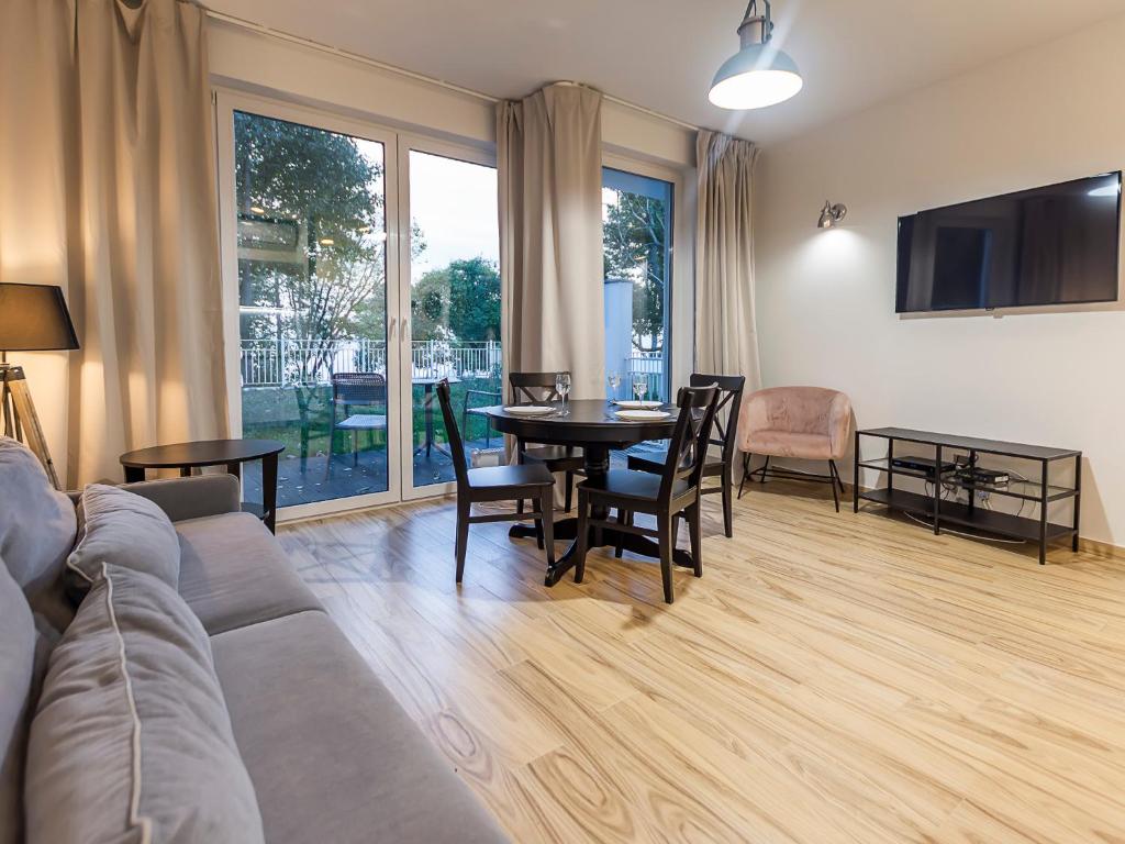een woonkamer met een bank en een tafel en stoelen bij VacationClub – Orłowska Riwiera Apartament A2 in Gdynia