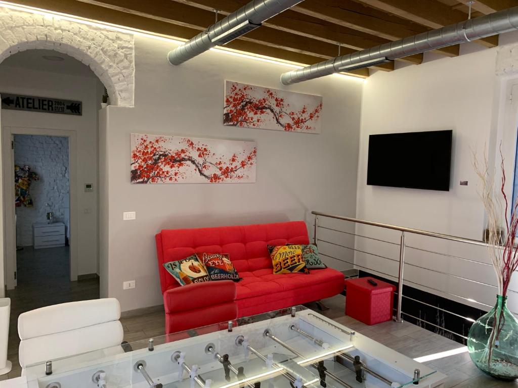 CA FOSCARI Loft & Factory في ميلانو: غرفة معيشة مع أريكة حمراء وتلفزيون