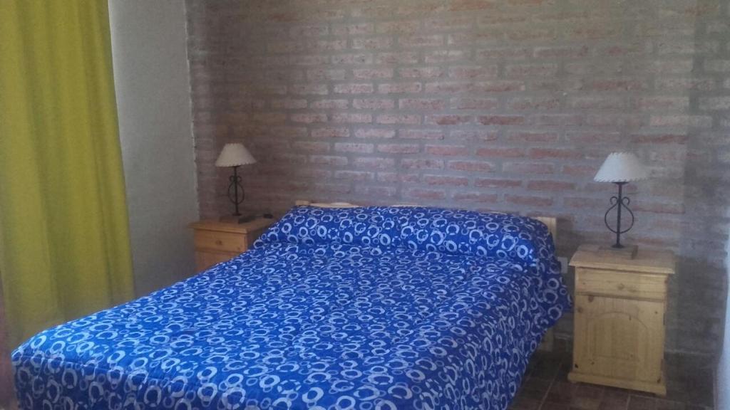 1 cama con edredón azul en un dormitorio en Cabañas Hilario en Los Reartes
