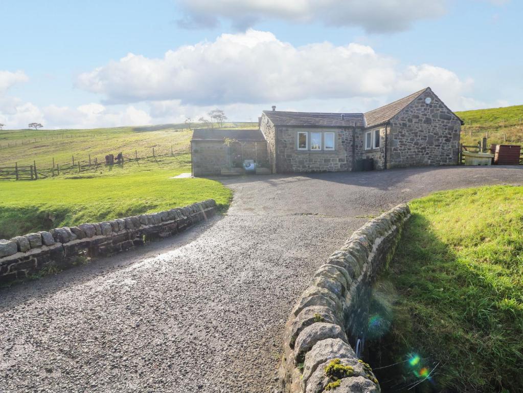 a stone house in a field with a stone wall at Beckside Cottage in Keighley