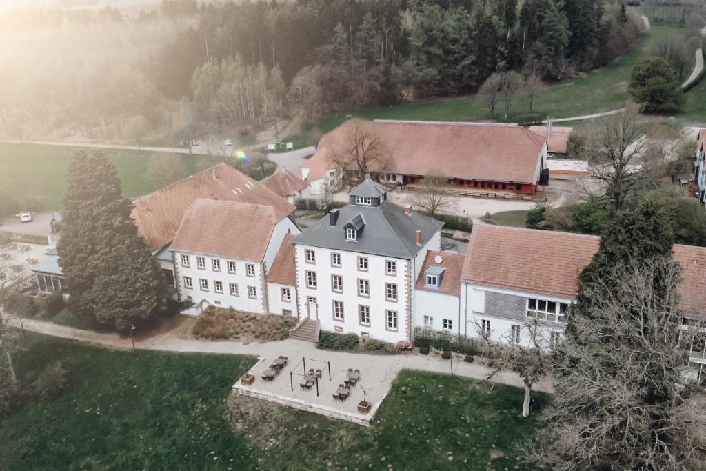 Hotel Hofgut Imsbach Lapointe في Tholey: اطلالة جوية على بيت ابيض كبير