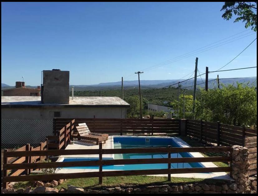 a swimming pool with two chairs and a fence at CABAÑA EN TANTI in Tanti