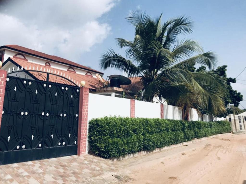 a house with a black gate and a palm tree at Charming 2-Bed House in Brusubi in Brusubi