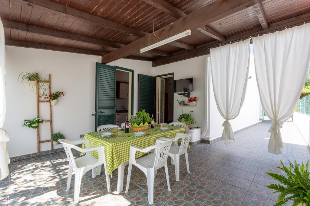 a dining room with a green table and white chairs at Villa Cielo e Terra by BarbarHouse in Torre Suda