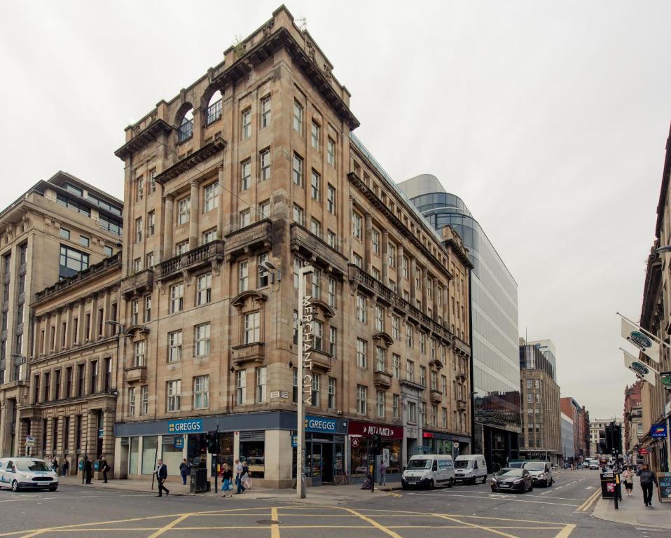 グラスゴーにあるPREMIER SUITES PLUS Glasgow George Squareの車を停めた街路の高い建物