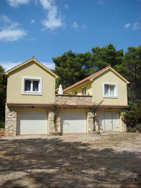 a house with two garage doors in a yard at Villas Oleandri in Vrboska