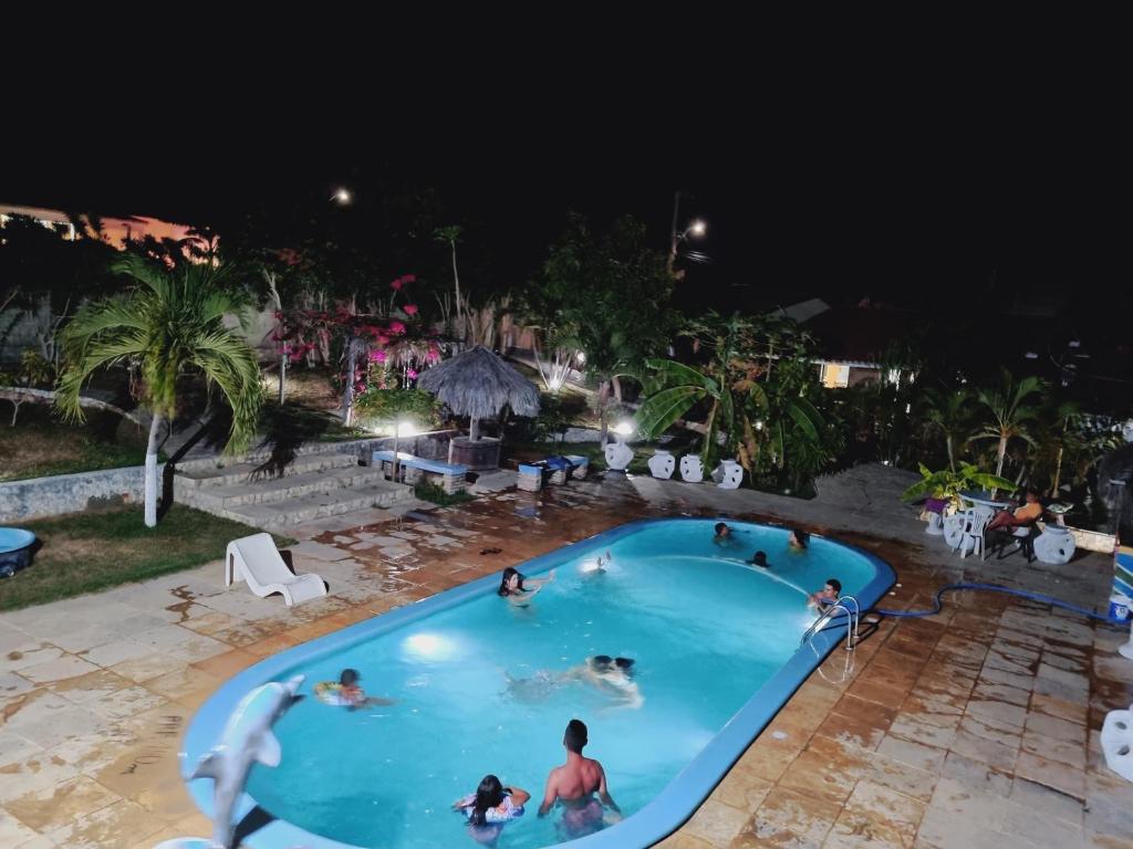 un grupo de personas en una piscina por la noche en Casa do Galego no Residência Família en Canoa Quebrada