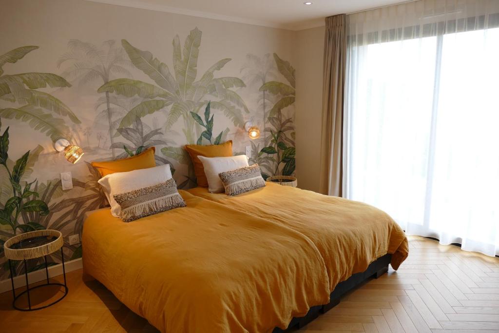 - une chambre dotée d'un grand lit avec des draps jaunes dans l'établissement Les Agapanthes, à Camphin-en-Pévèle