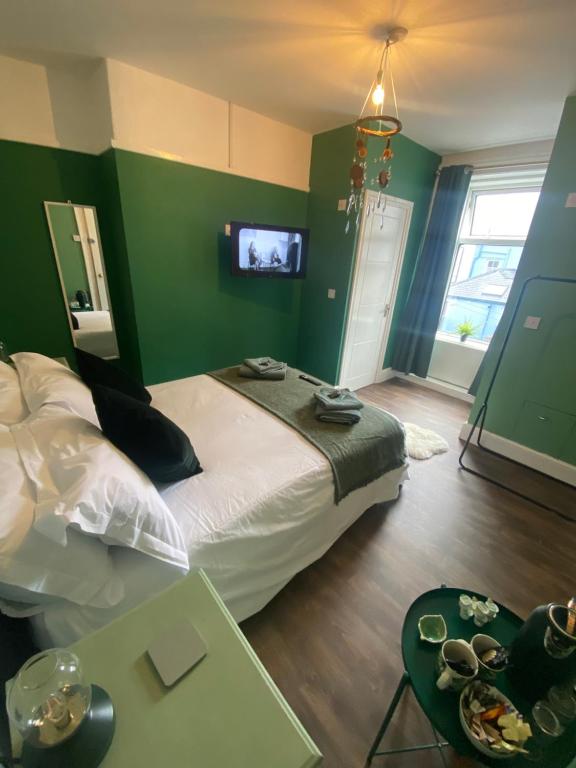 a bedroom with a bed with green walls and a tv at Tegfan -The Anglesey Townhouse in Caernarfon