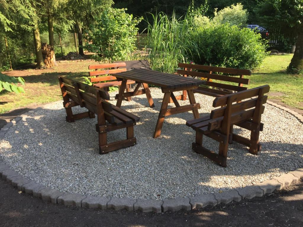 drei Holzbänke und ein Picknicktisch in einem Park in der Unterkunft FEWO am Wald in Krauschwitz