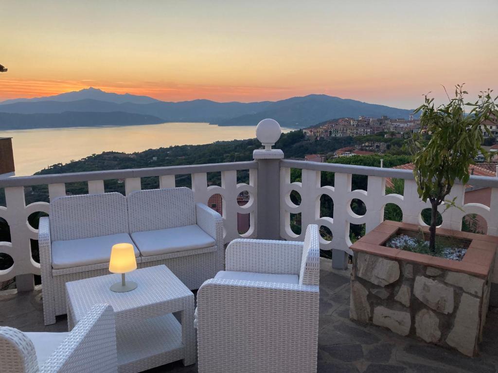 einen Balkon mit Stühlen, einem Tisch und einem Sonnenuntergang in der Unterkunft SUNSET SUITE in Capoliveri