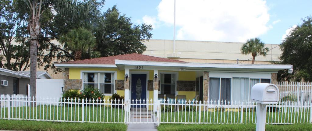 a white fence in front of a yellow house at Traditional Cozy Historic Tampa Home in Tampa