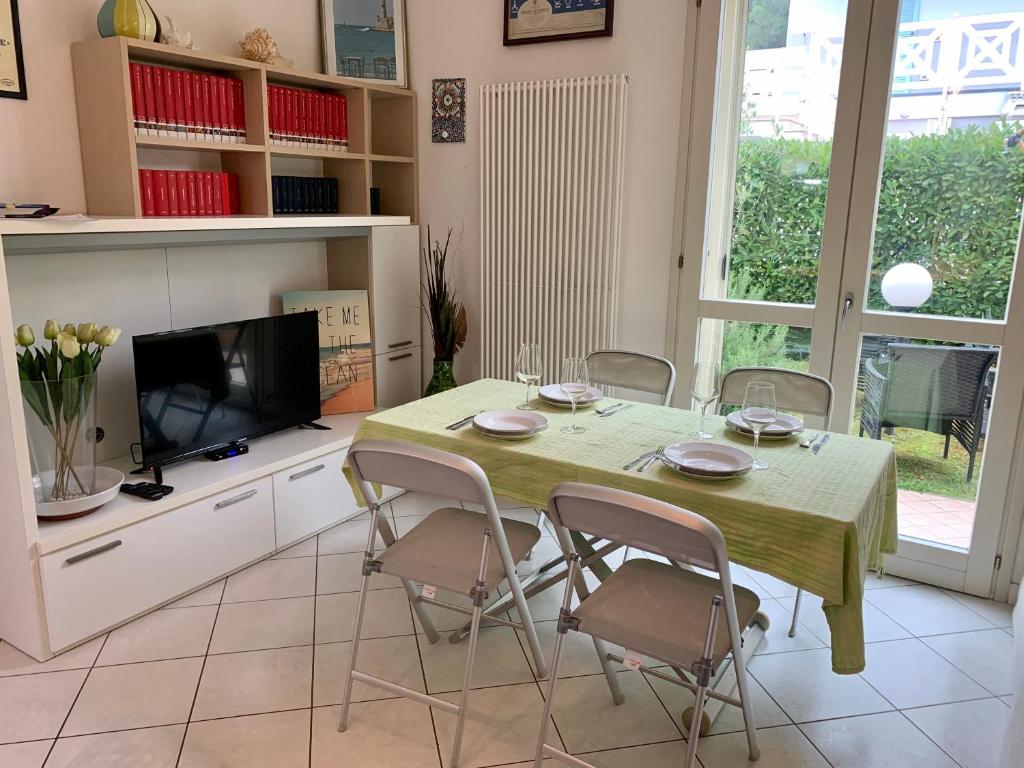 een eetkamer met een tafel met stoelen en een televisie bij MedusaBlu121 in Punta Marina