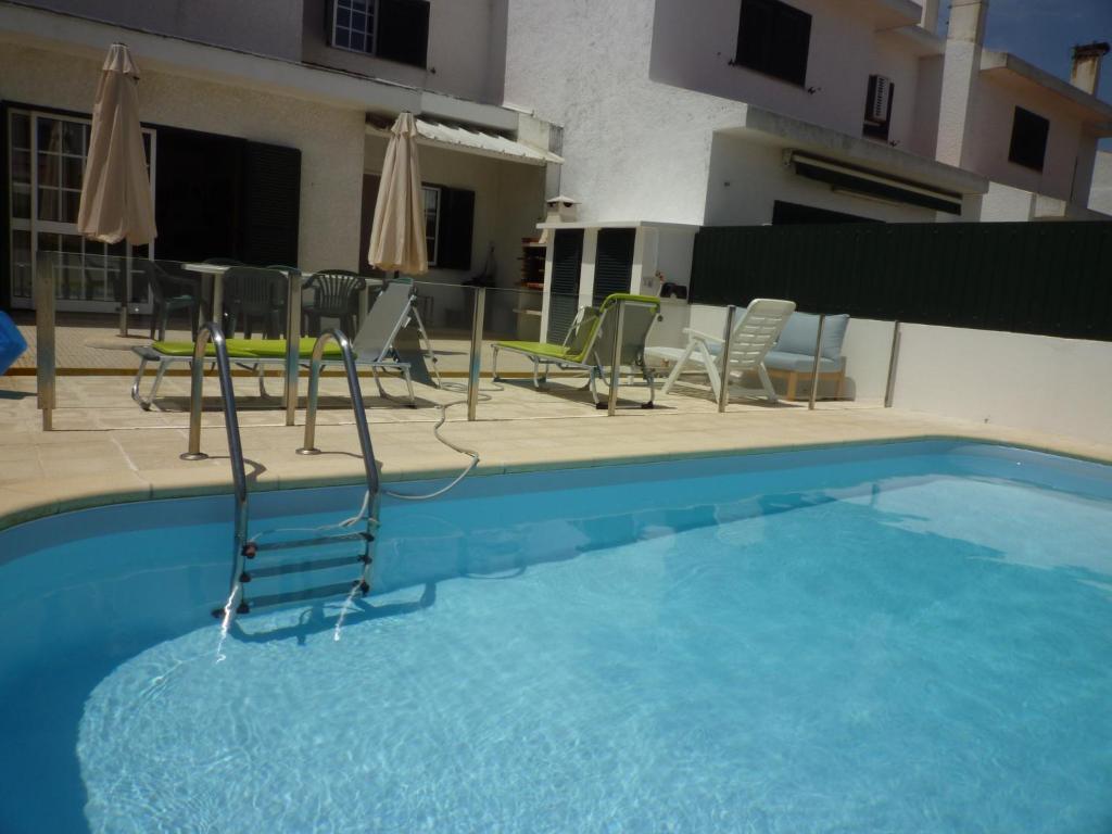 una piscina azul con sillas y sombrillas en Casa Praia e Ria, en Torreira