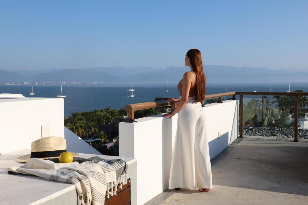 kobieta stojąca na balkonie z widokiem na ocean w obiekcie Kovay Gardens w mieście Cruz de Huanacaxtle