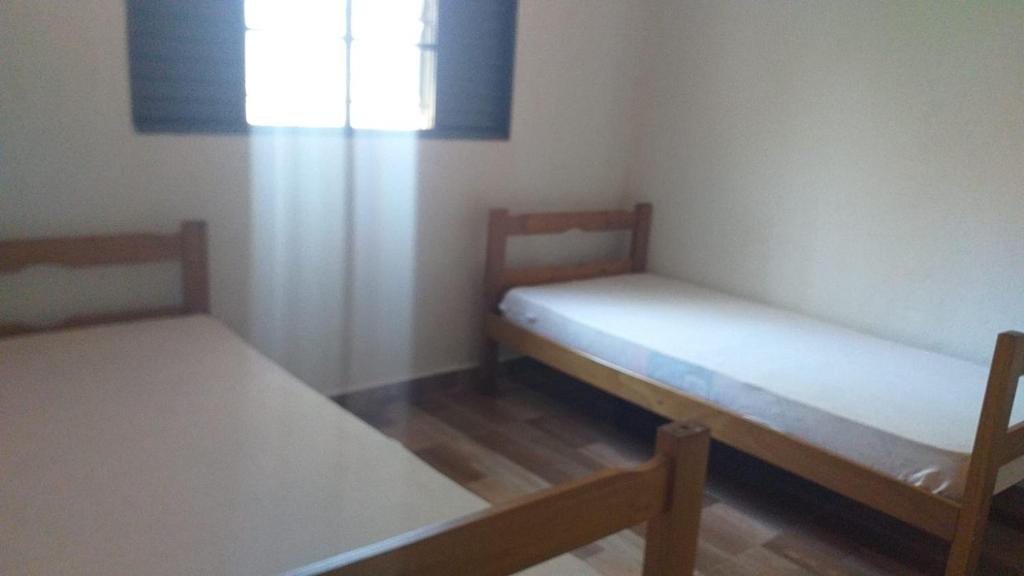 two beds in a small room with a window at Chácara São Francisco in Olímpia