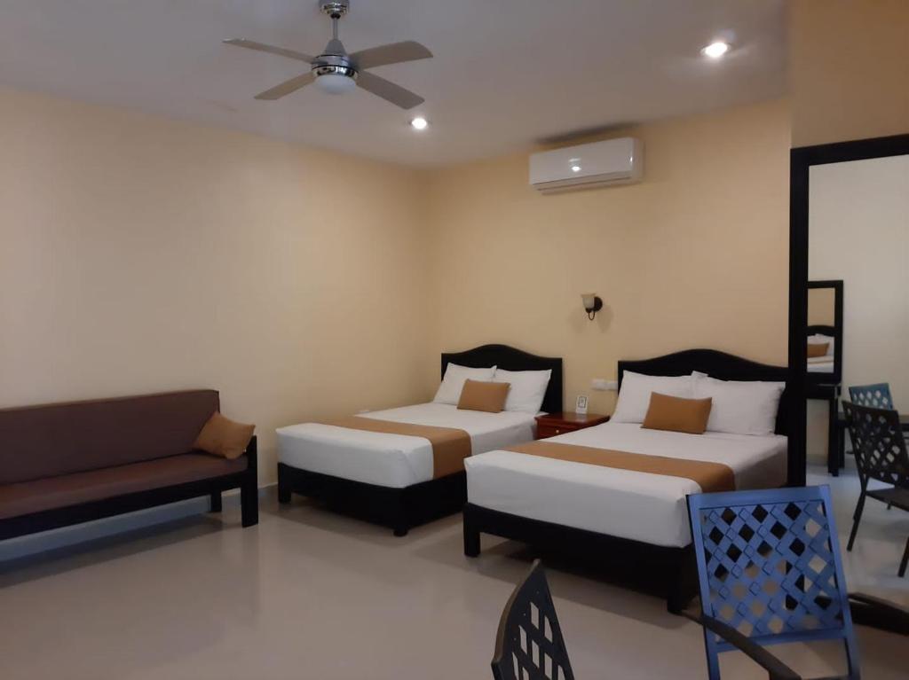 une chambre d'hôtel avec deux lits et un canapé dans l'établissement Departamentos X`Kanlol, à Izamal