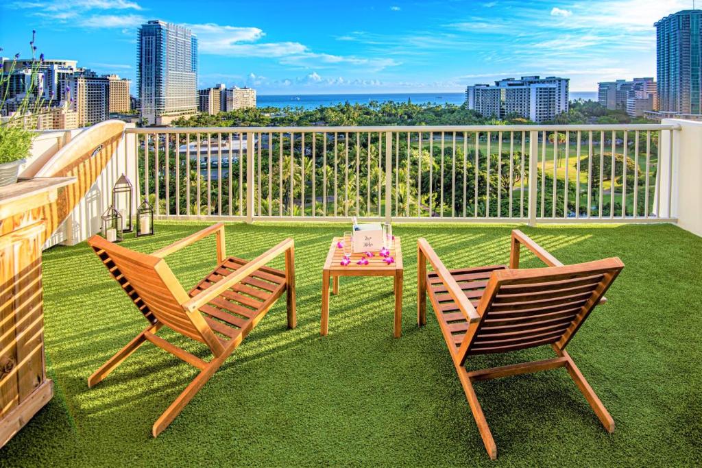 een patio met 2 stoelen en een tafel op een balkon bij Hotel La Croix in Honolulu
