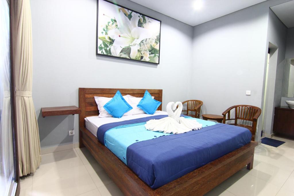 a bedroom with a bed with blue sheets and blue pillows at Radha Homestay in Sanur