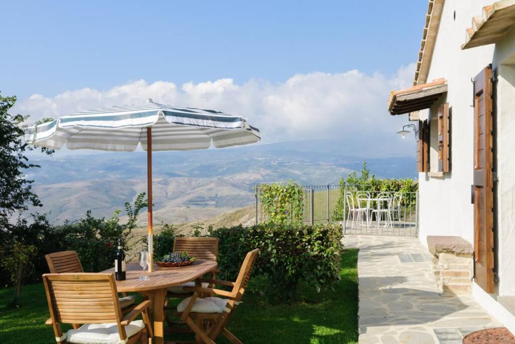 a table and chairs with an umbrella on a patio at Cottage Assolata overlooking the Orcia valley in Tuscany in Radicofani