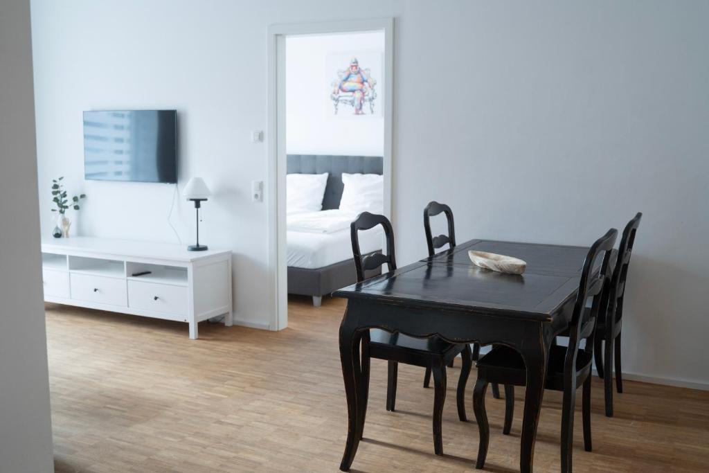 een eetkamer met een zwarte tafel en stoelen en een bed bij Prime Park Family Apartment Aschaffenburg in Aschaffenburg