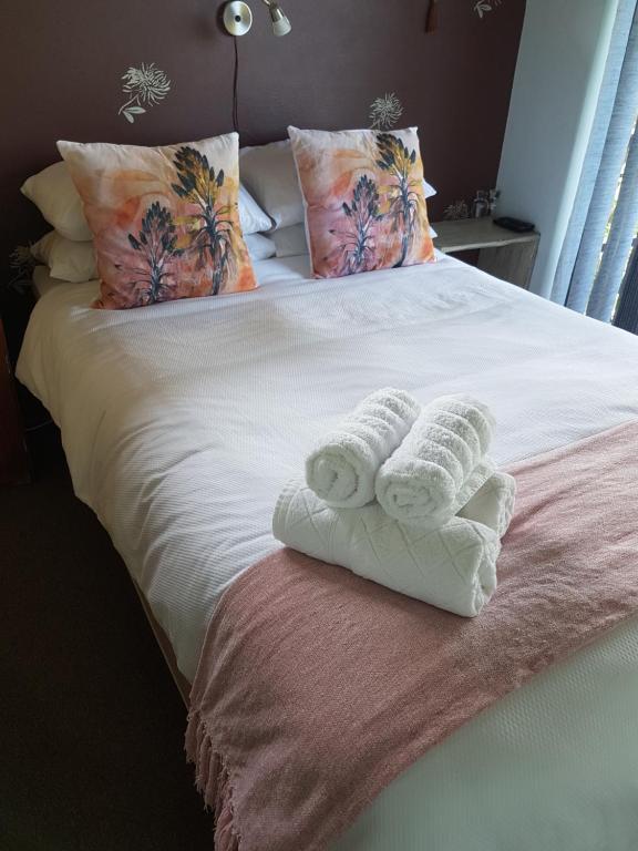 a bed with two rolled towels on top of it at Candleberry Stay in East London