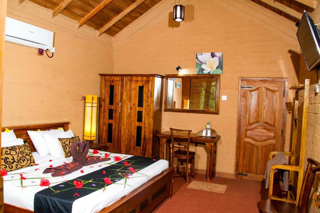 a bedroom with two beds and a table in it at Lotus Eco Villa in Sigiriya