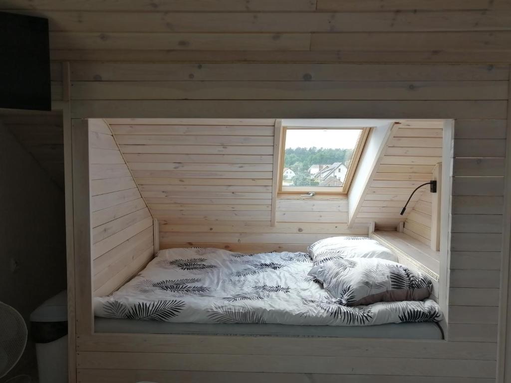 Łóżko w drewnianym pokoju z oknem w obiekcie PAKLADA 3 Pokój typu studio w mieście Karsin