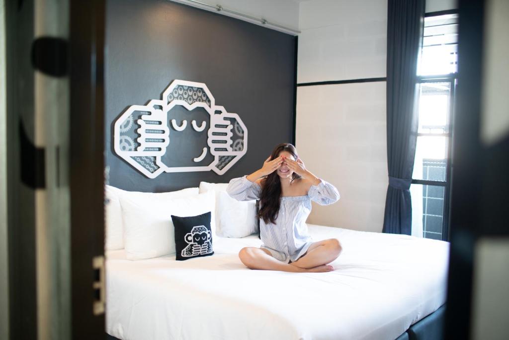 素叻的住宿－Blu Monkey Hub & Hotel Surat Thani，坐在卧室床上的女人