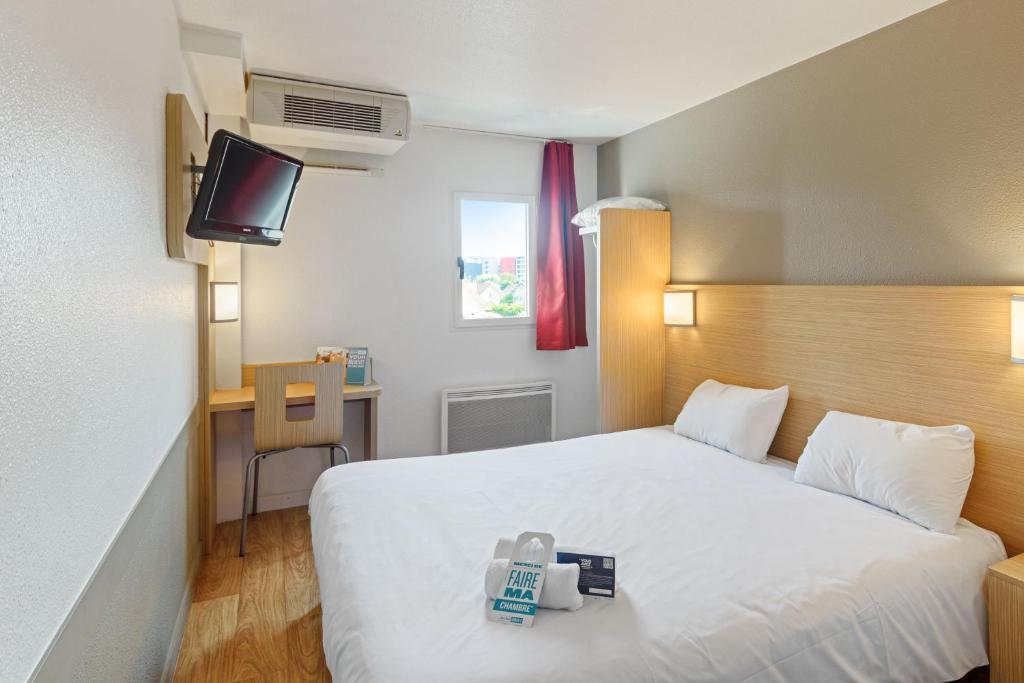 ein Hotelzimmer mit einem weißen Bett und einem Schreibtisch in der Unterkunft Kyriad Direct Annemasse - Genève in Gaillard