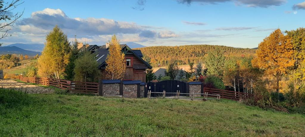 a house on a hill with a wooden fence at Chata drewniana Stefanówka in Ślemień