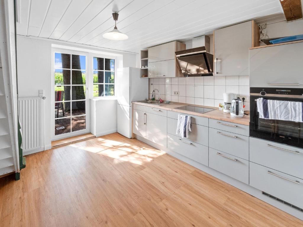 a kitchen with white cabinets and a wooden floor at Unterkunft für Monteure/ Geschäftsreisende bei Familie Bokeloh in Kirchlinteln